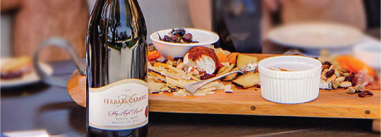 Bottle of Ferrari-Carano wine beside an elegantly arranged charcuterie board featuring assorted meats, cheeses, fruits, and nuts