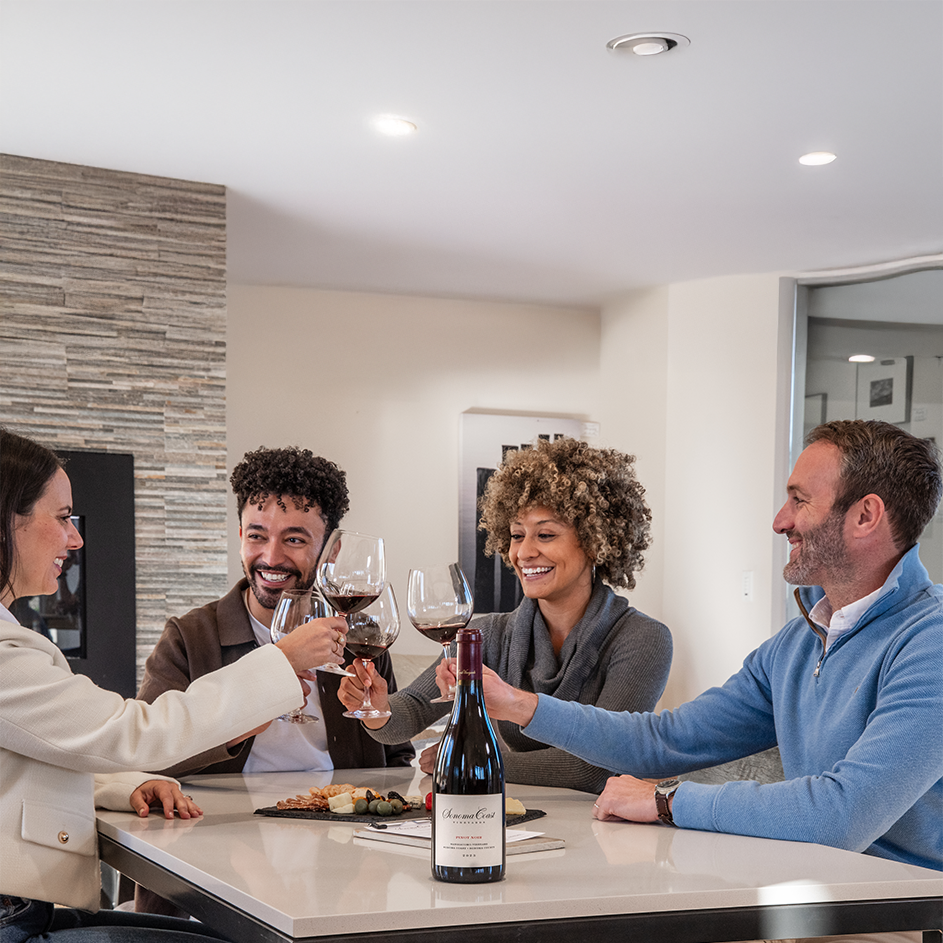 Group of friends toasting with Sonoma Coast wines around a kitchen island inside a home