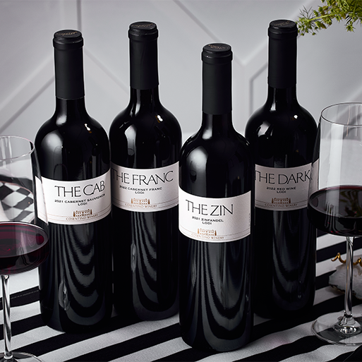 Four bottles of Cosentino THE series wines on a black and white stripped table cloth