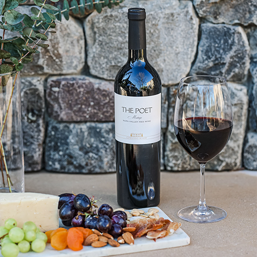 A bottle of Cosentino THE POET wine, next to a poured glass and charcuterie