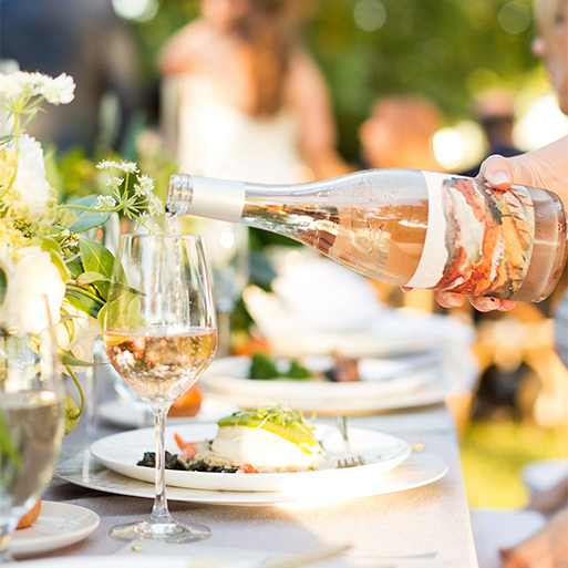 A vibrant table setting with plated foot as a person pours a glass of Foley Sonoma Rosé
