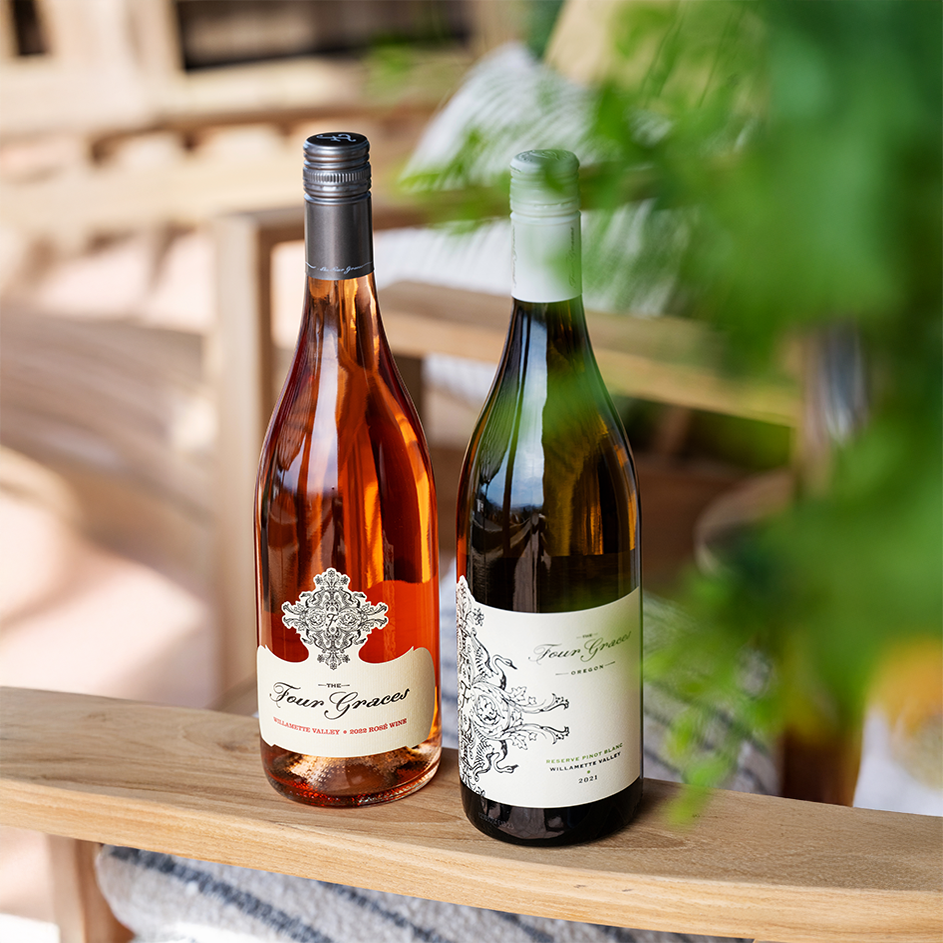 two bottles of the four graces wine on the arm of a wooden chair outdoors