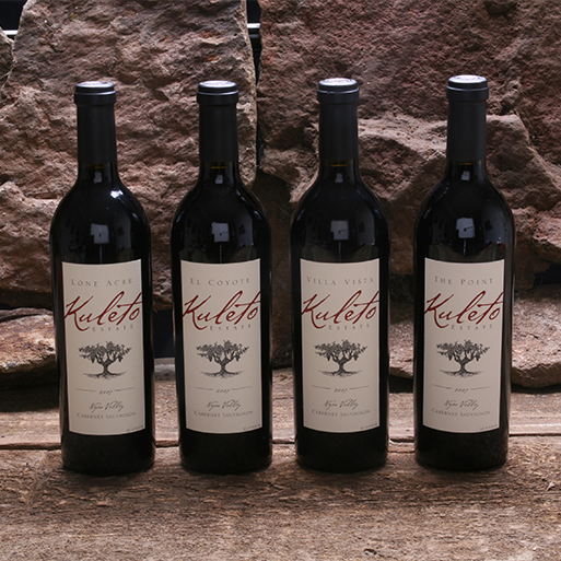 Four bottles of Kuleto wines in front of a rock wall