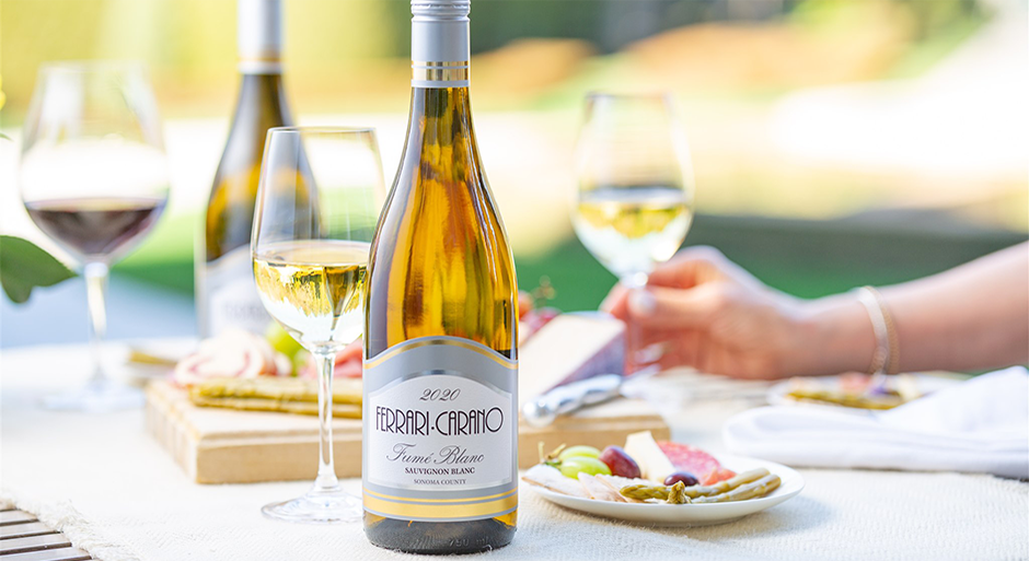 ferrari carano wines bottled and in glasses on a table with someone holding a glass of white wine
