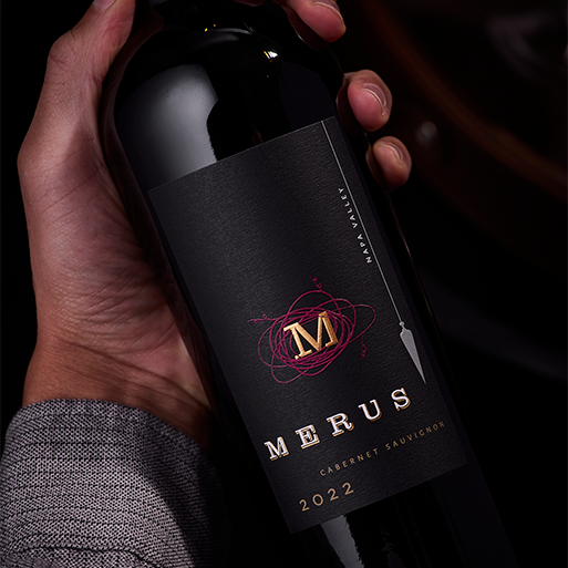 Close-up of a hand holding a bottle of Merus Cabernet Sauvignon wine