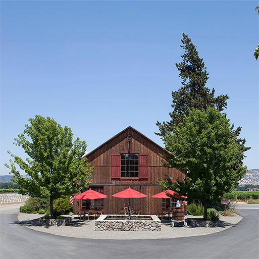Foley Johnson tasting room in Napa Valley with outdoor seating, large trees, and sunshine