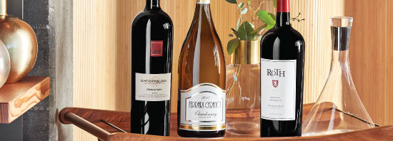 Bottle shot of three magnum-sized wine bottles displayed on a table, showcasing their unique labels and elegant shapes